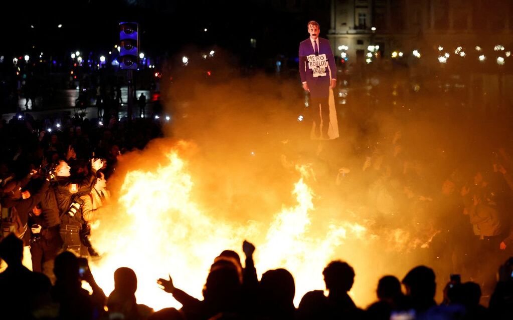 Las protestas contra la reforma de pensiones de Macron continúan escalando en violencia debido a la imposición por decreto. En la imagen, un grupo de manifestantes incendian la imagen del presidente.
