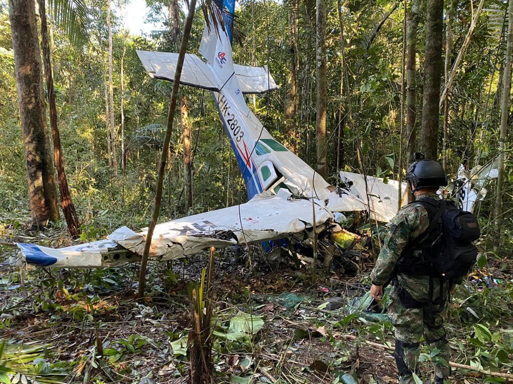 En esta foto proporcionada por la Oficina de Prensa de las Fuerzas Armadas de Colombia, un soldado permanece frente a los restos de una avioneta Cessna C206 el jueves 18 de mayo de 2023. La aeronave se estrelló en la selva de Solano, Colombia. Las autoridades buscan a cuatro niños indígenas que algunos piensan podrían haber sobrevivido el accidente en la selva amazónica el 1 de mayo. (Oficina de Prensa de las Fuerzas Armadas de Colombia, vía AP)