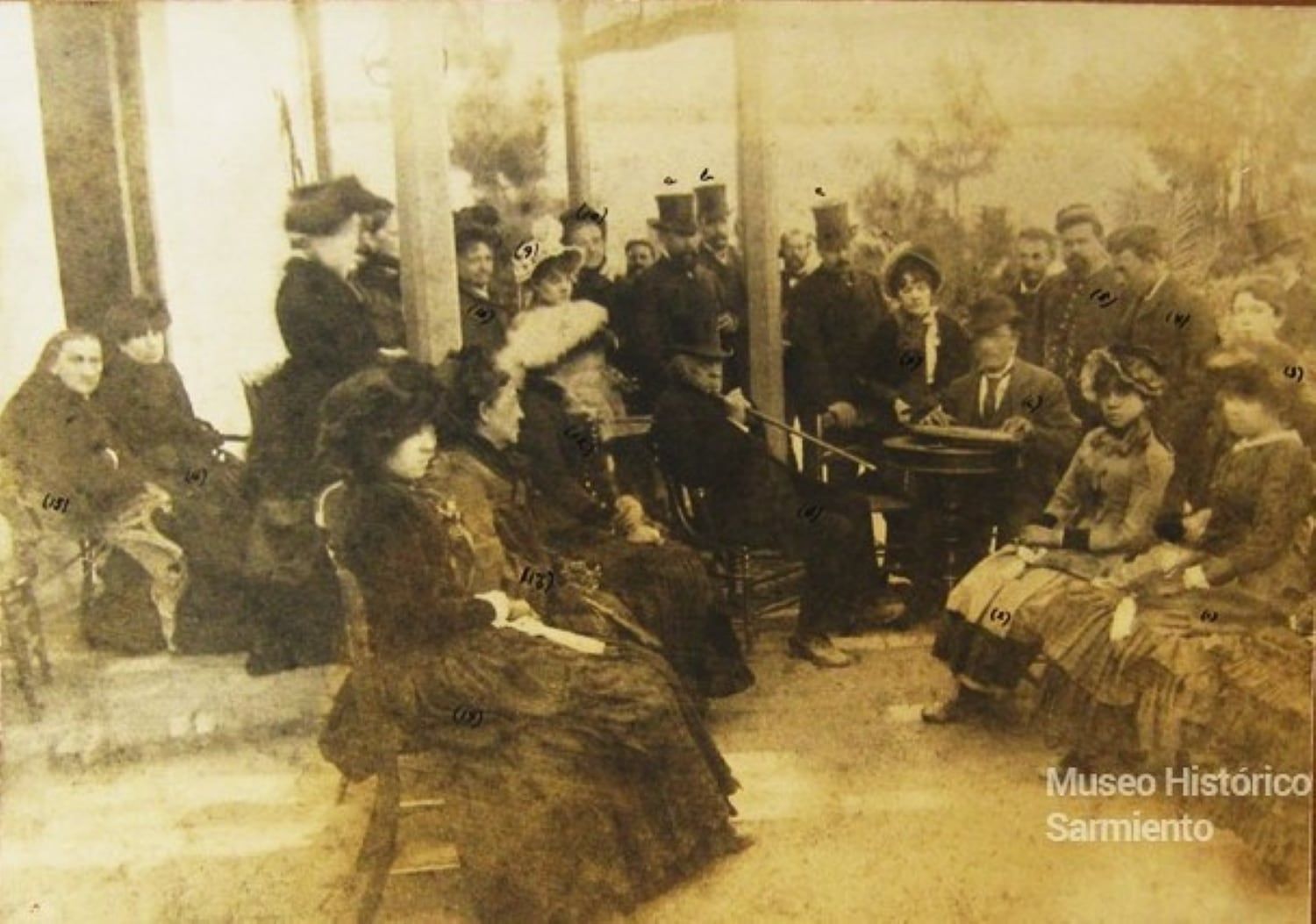 Domingo F. Sarmiento, se lo ve de piernas cruzadas en un cómodo sillón, en su mano derecha sostiene un bastón acústico, cuyo original se encuentra en el “Museo Histórico Sarmiento” de Buenos Aires; además estaban Ana Faustina Sarmiento de Belín ( hija ) que tenía 51 años entonces; Bienvenida Sarmiento, hermana mayor del prócer, tenía entonces 79 años; Eugenia Belín Sarmiento, Emilia Belín Sarmiento, Luisa Belín Sarmiento, las tres son nietas de D.F.Sarmiento, hijas de Ana Faustina. También Agustín Klappenbach (13 años) , nieto de Procesa Sarmiento, hermana menor del prócer. Entre las personalidades destacamos El Gobernador de la provincia Gral. Rufino Ortega; Francisco y Emilio Civit anfitriones (Sarmiento estuvo alojado en su casa, actual “Museo del Pasado Cuyano”) . También estaba un músico de origen sueco que toca una cítara.