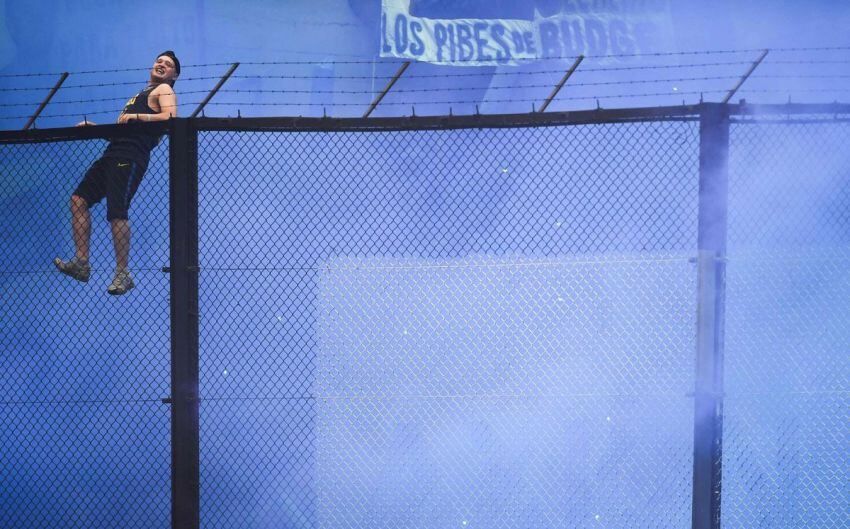  Foto: AFP | Un hincha se sube al alambrado de la tribuna antes del comienzo del partido.    