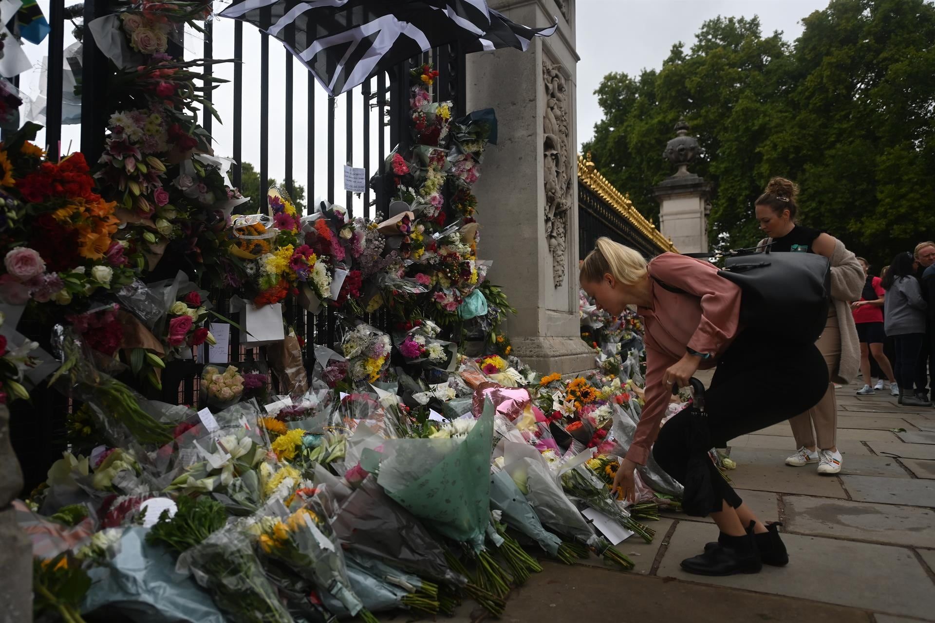 Una mujer deposita flores este viernes frente al palacio de Buckingham en Londres tras la muerte ayer de la reina Isabel II. / Foto: EFE