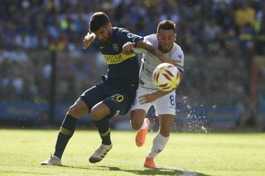 Sin rumbo. El debutante xeneize, Lisandro López, frena la marcha de Ángel González, del Tomba. | Télam