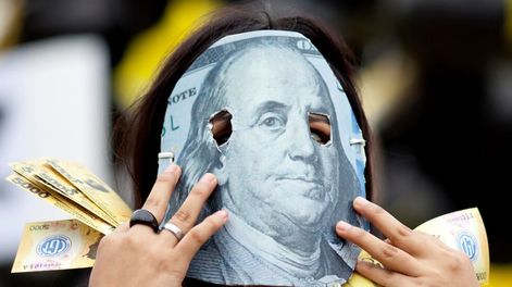 Los Andes | Una persona enmascarada con un detalle de un billete de 100 dólares, en protesta contra el acuerdo que firmó el gobierno de Mauricio Macri con el FMI.