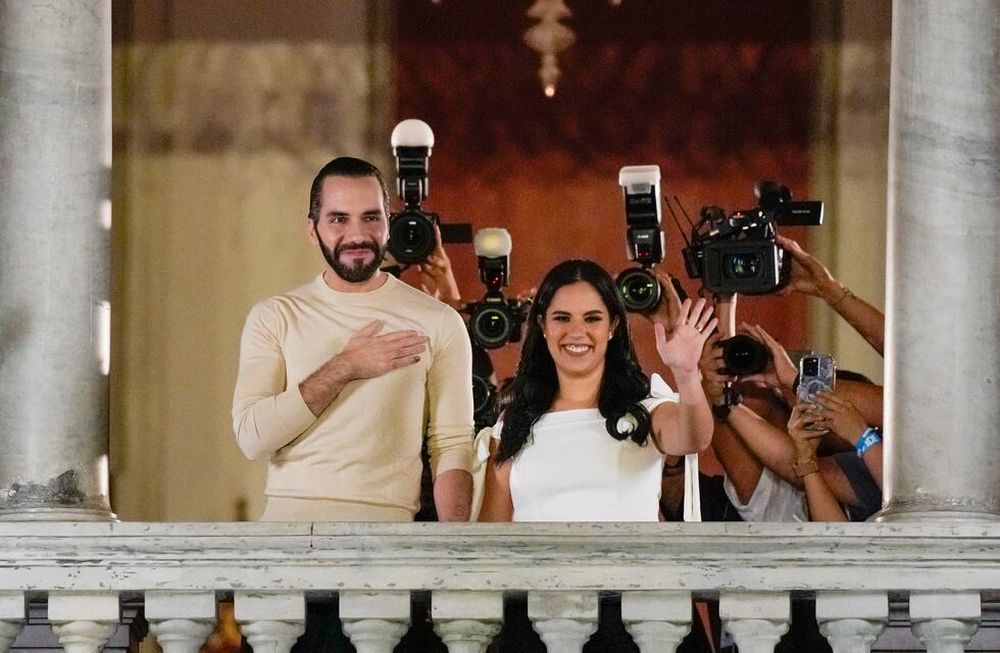 El presidente de El Salvador, Nayib Bukele, izquierda, acompañado por su esposa Gabriela Rodríguez, saluda a sus seguidores desde el balcón del palacio presidencial en San Salvador, después del cierre de las urnas para las elecciones generales del domingo 4 de febrero de 2024. (Foto AP /Moisés Castillo)