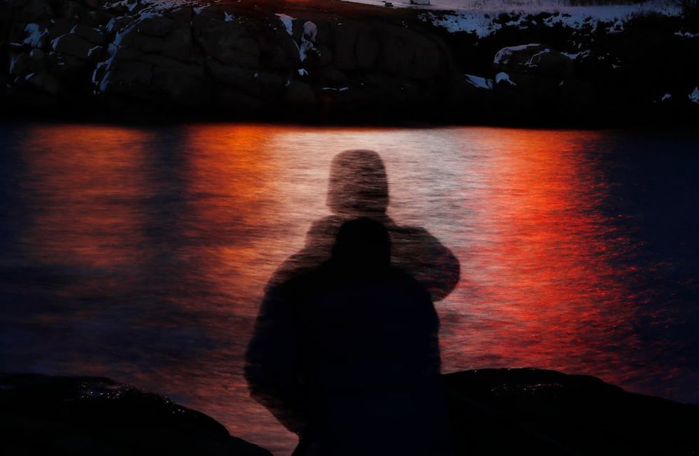 ARCHIVO - En esta fotografía de archivo, tomada con exposición prolongada, se ve la silueta de un hombre frente a luces reflejadas en las aguas de Cape Neddick, el 11 de diciembre de 2017, en Maine. (AP Foto/Robert F. Bukaty, archivo)