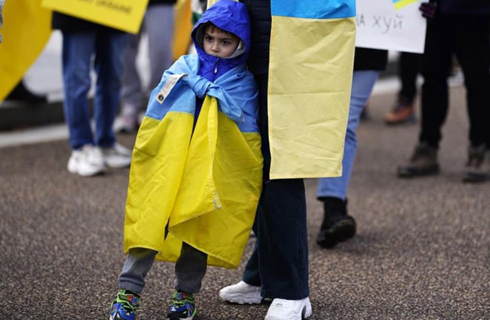 Un niño ucraniano refugiado junto a su padre en una manifestación. Foto: EFE