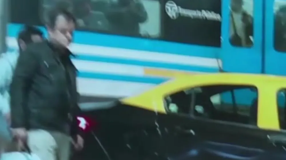 La imagen tomada por un testigo muestra al pasajero del taxi (con campera negra) y al conductor (al fondo, con campera blanca) tras el choque con el tren en Flores.
