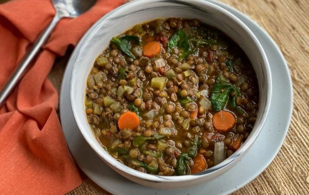 Un plato de lentejas acompañado por diferentes verduras y aceite de oliva combina legumbres, vegetales y una fuente de grasa insaturada.