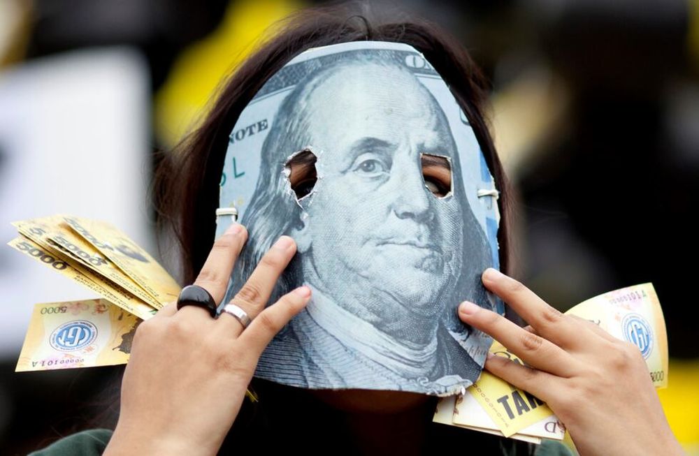 Una persona enmascarada con un detalle de un billete de 100 dólares, en protesta contra el acuerdo que firmó el gobierno de Mauricio Macri con el FMI.