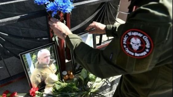 Un soldado con un parche del PMC Wagner deja flores en un altar con fotos de los líderes del grupo fallecidos.
