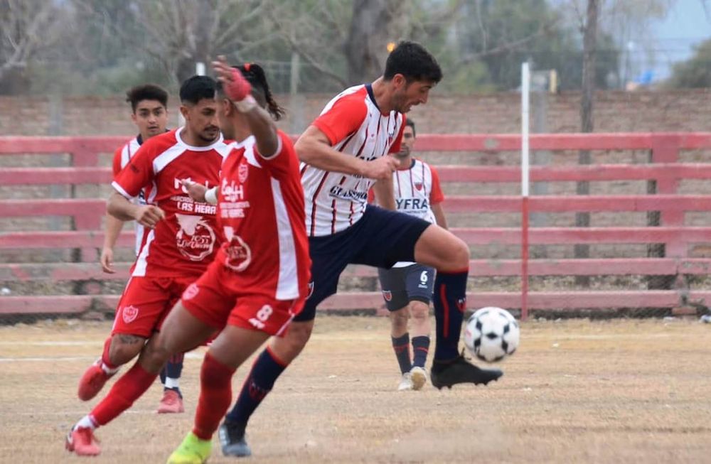 El Flaco Jesús Baldaccini se lleva el balón ante la marca de dos jugadores de Algarrobal. Talleres goleó y manda en la zona A. / Gentileza Andrés Arequipa.