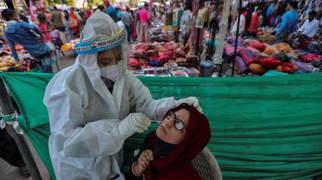 Un trabajador de la salud toma una muestra de hisopado nasal de una mujer para realizar la prueba de COVID-19 en una instalación construida en un mercado en Ahmedabad, India. Foto: AP