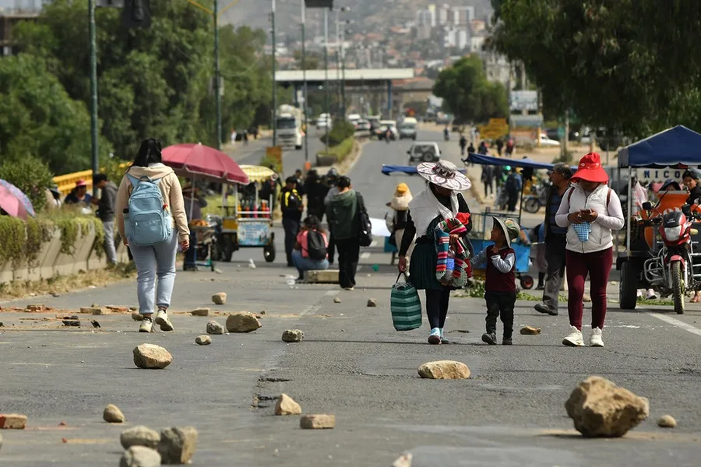 Personas caminan en una ruta bloqueada durante una protesta para pedir la renuncia del presidente de Bolivia, Rodrigo Paz.