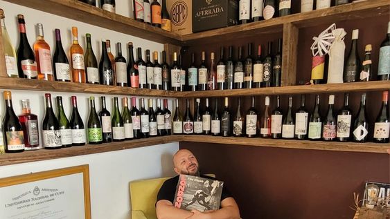 En un rincón de su estudio en La Consulta, Daniel posa rodeado de botellas que en la etiqueta llevan su autoría, sosteniendo un disco de The Clash y junto su título de la UNCuyo.
