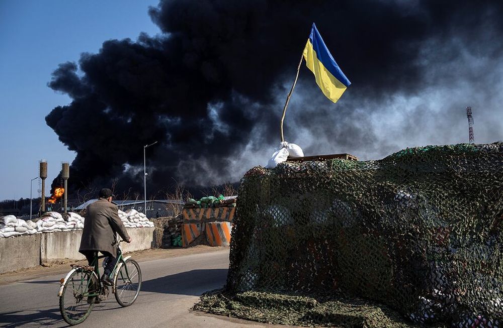 Ucrania. Un hombre anda en bicicleta mientras, de fondo, se levanta una columna de humo negra tras ataques rusos en las afueras de Kiev. (AP / Rodrigo Abd)