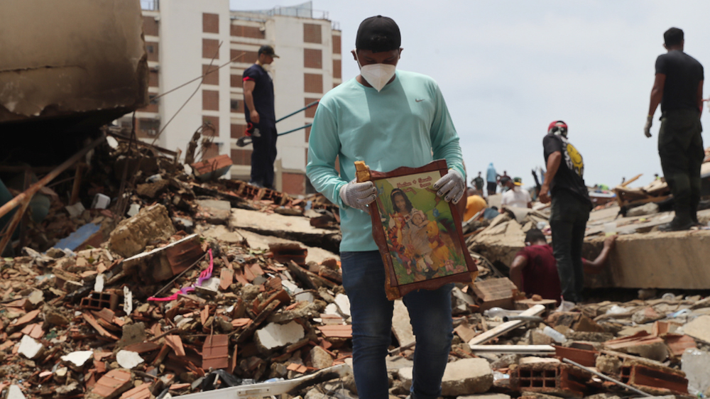 Un hombre sostiene un cuadro sobre escombros de edificaciones destruidas en La Guaira, Venezuela. (archivo)
