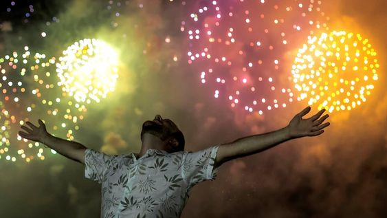 Un hombre celebra el inicio del año nuevo, con el telón de fondo de la explosión de fuegos artificiales en el fondo sobre la playa de Copacabana en Río de Janeiro, Brasil