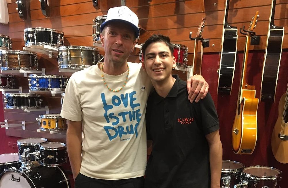 Martin junto a uno de los vendedores que lo recibió. El inglés tocó junto a los trabajadores del local y les regaló entradas. (Twitter).