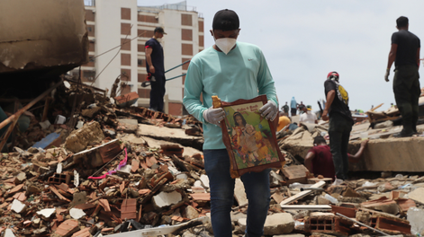 Un hombre sostiene un cuadro sobre escombros de edificaciones destruidas este martes, en La Guaira (Venezuela)