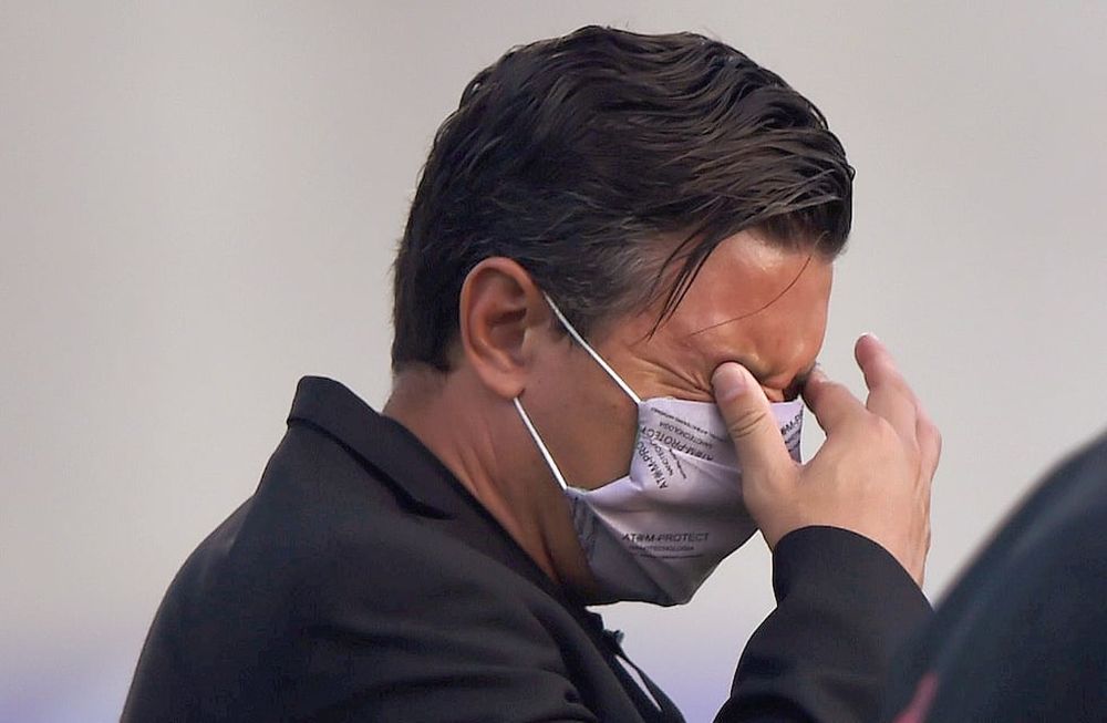 El DT. Marcelo Gallardo se tapa los ojos, afectado por los gases lacrimógenos que llegaron al estadio en el que se jugaba Junior de Barranquila ante River. (AP)