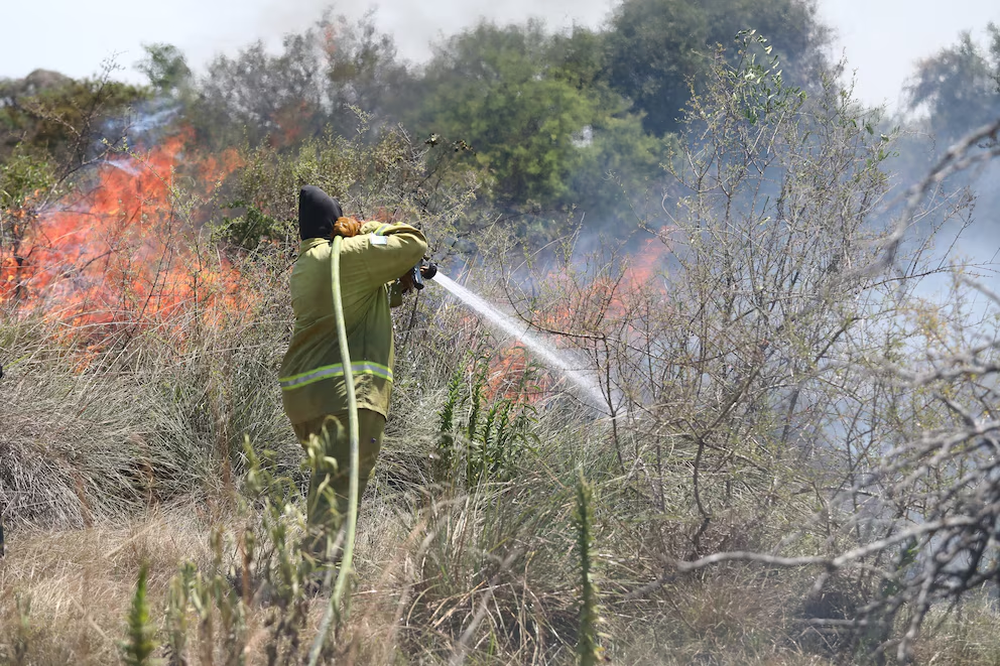 Bomberos voluntarios lanzan agua contra las llamas en los incendios forestales de Corrientes.