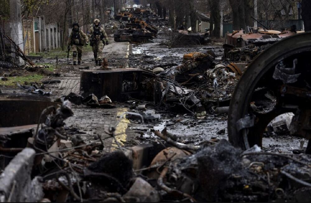 Soldados caminan entre tanques rusos destruidos en Bucha, en las afueras de Kiev, Ucrania, el domingo 3 de abril de 2022. (AP)