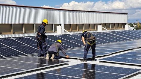 Personal instalando paneles solares en una empresa.