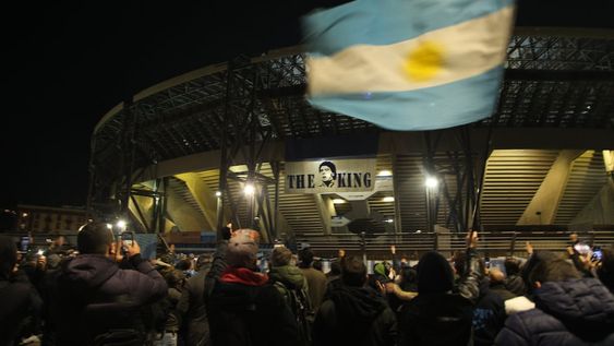 People gather at the main entrance of the San Paolo stadium in Naples on November 25, 2020 in front of an image of Argentinian football legend Diego Maradona reading The King, to mourn after the annoucements of Maradonas death. - Argentine football legend Diego Maradona has died at the age of 60, his spokesman announced November 25, 2020. (Photo by CARLO HERMANN / AFP)