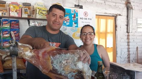 Alejandro y Natalia en su negocio, mostrando los jamones de San Rafael. | Foto: gentileza