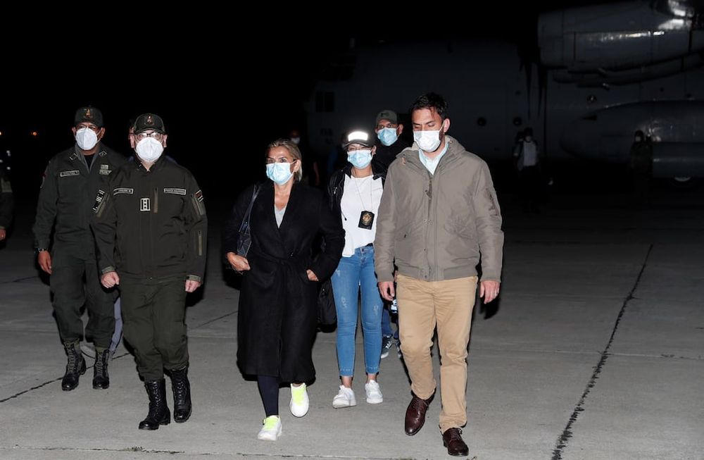 La ex presidenta interina de Bolivia, Jeanine Anez, centro, es escoltada por el ministro de gobierno Carlos Eduardo Del Castillo, derecha, y el comandante de la policía boliviana Jhonny Aguilera, izquierda. AP