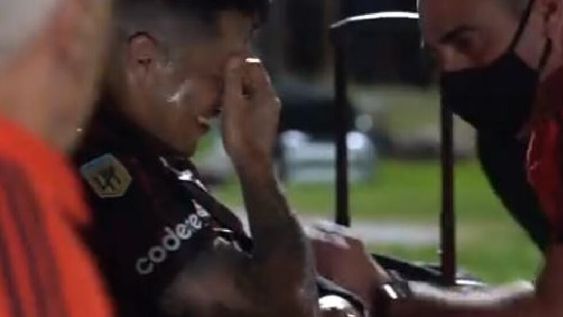 Enzo Pérez y el codo fuera de posición, tras la fuerte caída. El kinesiólogo del equipo lo atiende y trata de animarlo. /Captura de video.