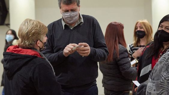 El intendente Daniel Orozco le entrega y explica el resultado del test de anticuerpos a una de las vecinas en la que se realizó los estudios.