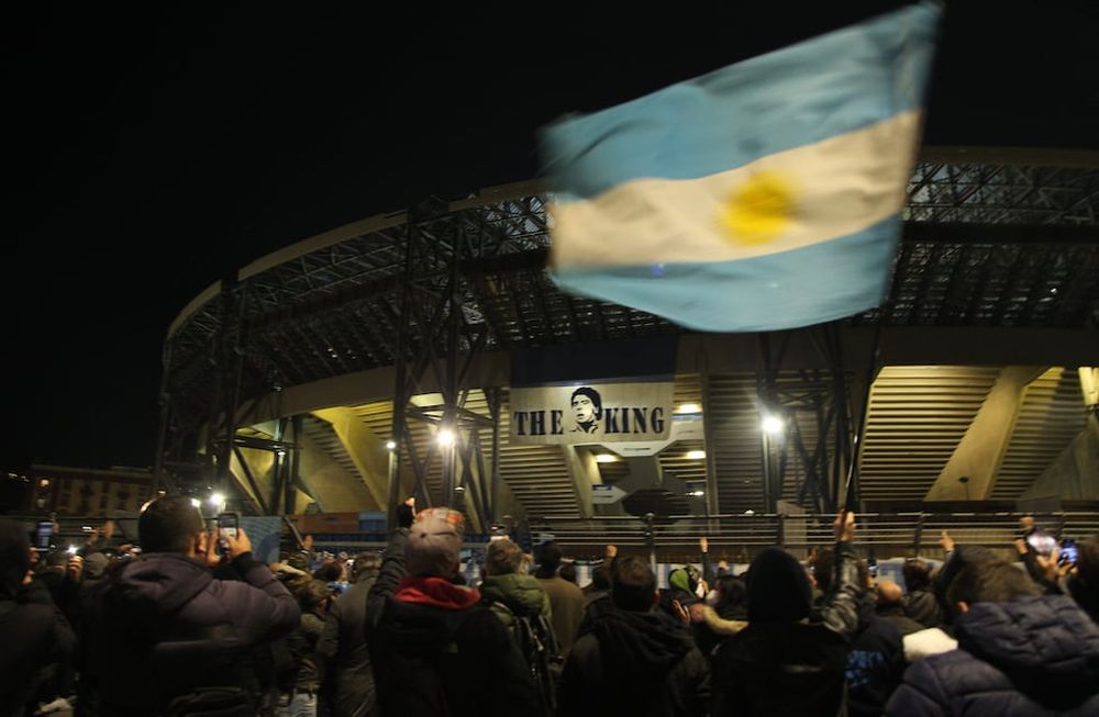 People gather at the main entrance of the San Paolo stadium in Naples on November 25, 2020 in front of an image of Argentinian football legend Diego Maradona reading The King, to mourn after the annoucements of Maradonas death. - Argentine football legend Diego Maradona has died at the age of 60, his spokesman announced November 25, 2020. (Photo by CARLO HERMANN / AFP)