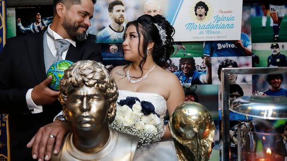 La pareja mexicana Jaziel Torres (i) y Héctor García (c) posan en una motocicleta tras su matrimonio de la Iglesia Maradoniana de México, el 1 de octubre de 2022, en el municipio de San Andrés Cholula, Puebla (México). EFE/Hilda Ríos