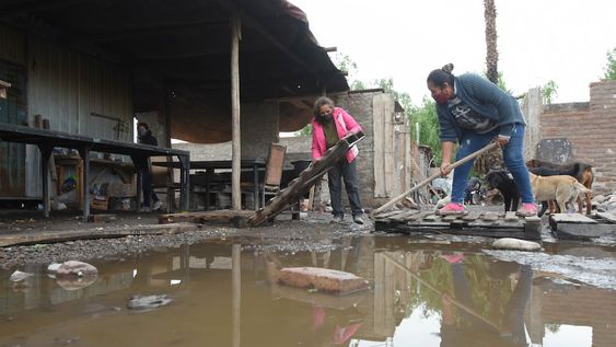Inundados. Silvia y Ariadna, del merendero Corazones Felices, de El Sauce, Guaymallén, trabajan haciendo canaletas para que  corra el agua en el lugar donde comen los niños almuerzan. Foto: José Gutiérrez / Los Andes.