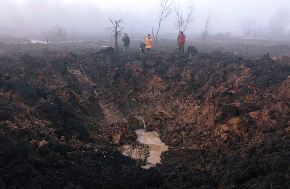 Los lugareños se reúnen alrededor de un cráter de bombardeo después de que un cohete golpeó el vecindario de Pisochyn en las afueras de Kharkiv. EFE