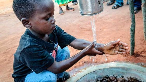 Un niño se lava las manos con agua que brota de una lata, luego de hacer fila para poder acceder a ella. El agua potable es un bien muy escaso.