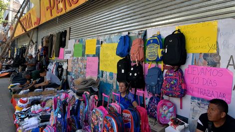 Los Andes | peligro. Los feriantes se instalaron en la vereda Norte de calle General Paz, en el frente de la propiedad incendiada y entre palos que apuntalan las paredes. | Foto: Orlando Pelichotti / Los Andes