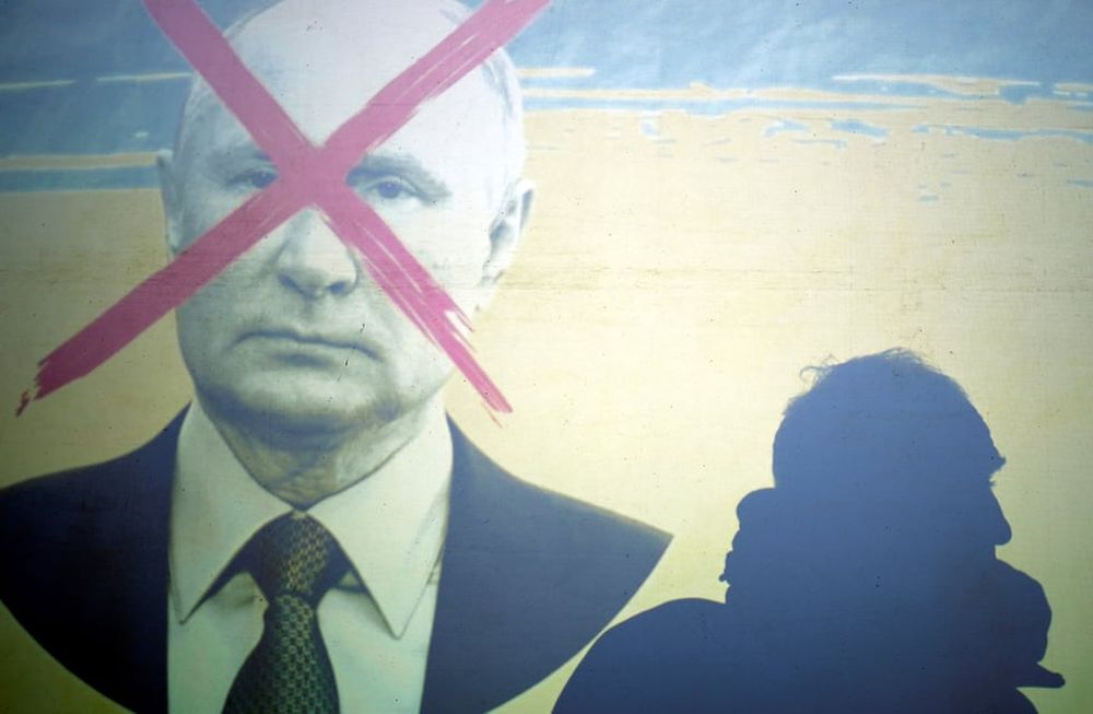 La silueta de un hombre en una pantalla que representa al presidente de Rusia, Vladimir Putin, durante una manifestación contra la invasión rusa de Ucrania. (AP)