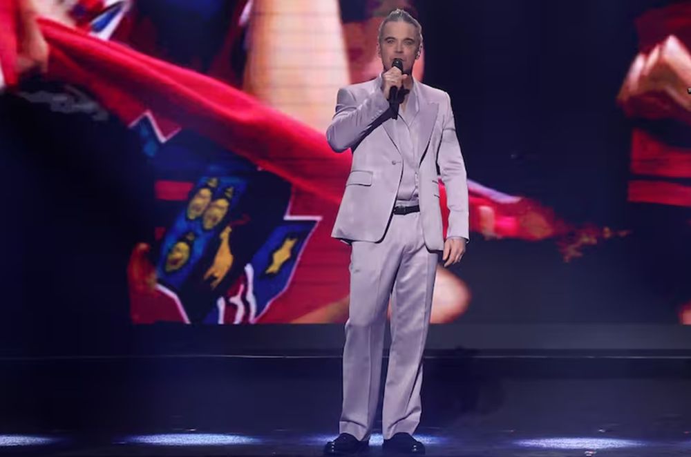 El cantante británico, de traje lavanda, fue captado ajustándose el pantalón en pleno show en vivo, en una escena que se volvió viral en redes.