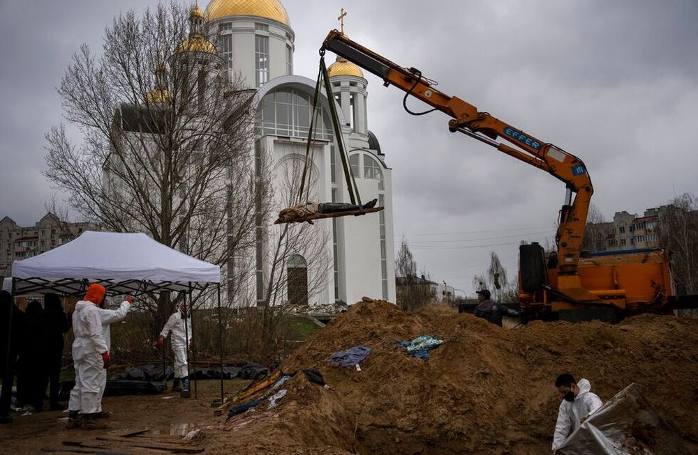 Una grúa levanta un cadáver de una fosa común con el fin de que sea trasladado a una morgue para su identificación, en Bucha, a las afueras de Kiev, Ucrania. / Foto: AP