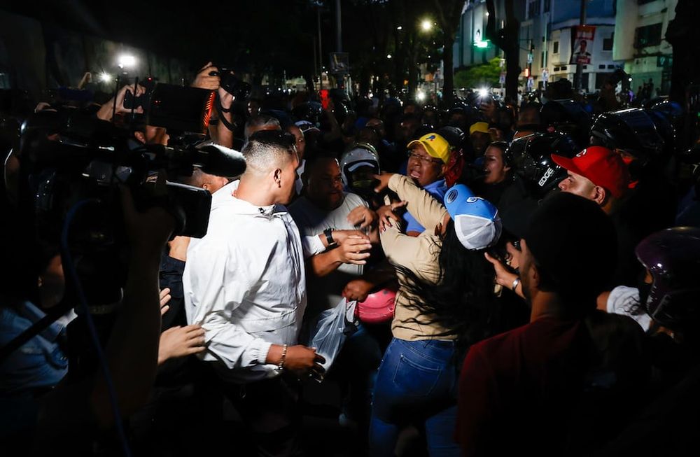Seguidores del presidente de Venezuela y candidato a la reelección, Nicolás Maduro, bloquean el acceso a personas que intentan entrar a un centro de votación para el conteo de votos este domingo, en Caracas (Venezuela). Varias decenas de motorizados que se identificaron como chavistas llegaron a un centro de votación en Caracas, donde se encontraban testigos opositores y ciudadanos que esperaban el comienzo del escrutinio de las elecciones presidenciales de este domingo, lo que dio lugar a una confrontación que acabó a golpes, ante la mirada impasible de los policías, que no intervinieron para detener la pelea. EFE/ Henry Chirinos