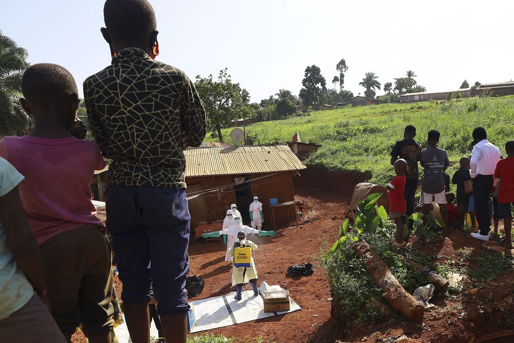 Médicos portando trajes de protección mientras son desinfectados previo al entierro de una víctima de ébola, en Mongbwalu, República Democrática del Congo (RDC).
