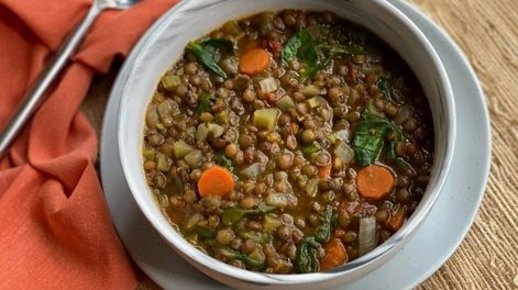 Un plato de lentejas acompañado por diferentes verduras y aceite de oliva combina legumbres, vegetales y una fuente de grasa insaturada.