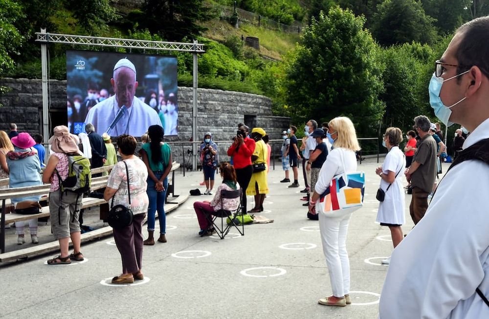 Fieles con máscaras protectoras siguen las medidas de distanciamiento social en la Grotte de Massabielle en el Santuario de Nuestra Señora de Lourdes, en Lourdes. AFP