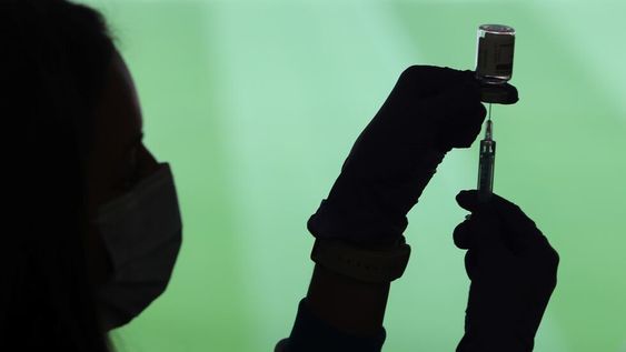 Un profesional sanitaria sostiene una jeringuilla y un vial con la vacuna del Covid-19, en un dispositivo instalado en el Estadio Wanda Metropolitano, en Madrid (España), a 30 de marzo de 2021.