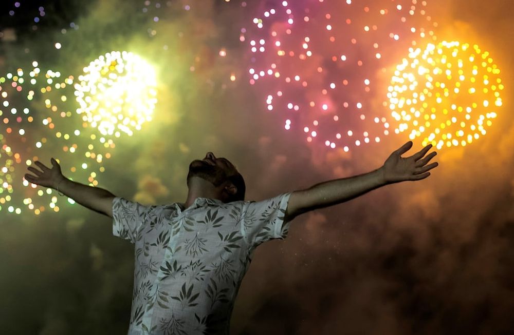 Un hombre celebra el inicio del año nuevo, con el telón de fondo de la explosión de fuegos artificiales en el fondo sobre la playa de Copacabana en Río de Janeiro, Brasil