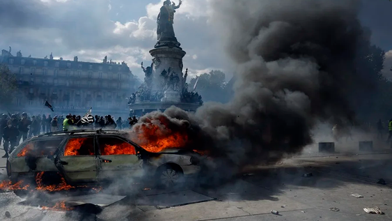 Un auto arde en la plaza de la República mientras estallan enfrentamientos entre manifestantes y la policía durante una protesta contra el aumento del coste de la vida y los recortes en París, Francia.