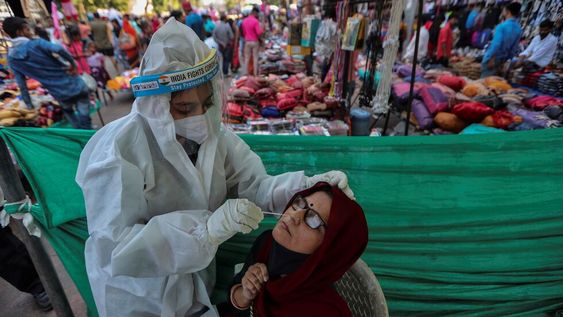 Un trabajador de la salud toma una muestra de hisopado nasal de una mujer para realizar la prueba de COVID-19 en una instalación construida en un mercado en Ahmedabad, India. Foto: AP