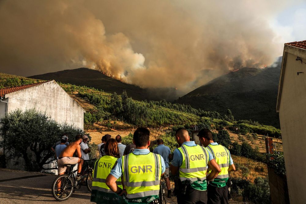 Miembros de la Gendarmería Nacional (GNR) se reúnen mientras un incendio forestal arde en la localidad de Chao Sobral, en el centro de Portugal, el 13 de agosto de 2025. El incendio, que comenzó en la cercana localidad de Piodao, se ha extendido a la vecina Arganil y a otras zonas, lo que ha provocado el despliegue de más de 600 bomberos.
